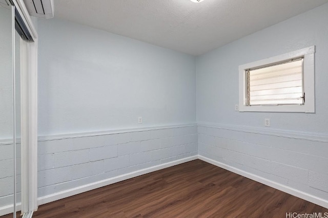 spare room featuring dark wood-type flooring and a textured ceiling