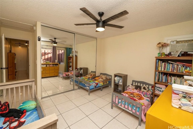 bedroom featuring a textured ceiling, a closet, tile patterned floors, and ceiling fan