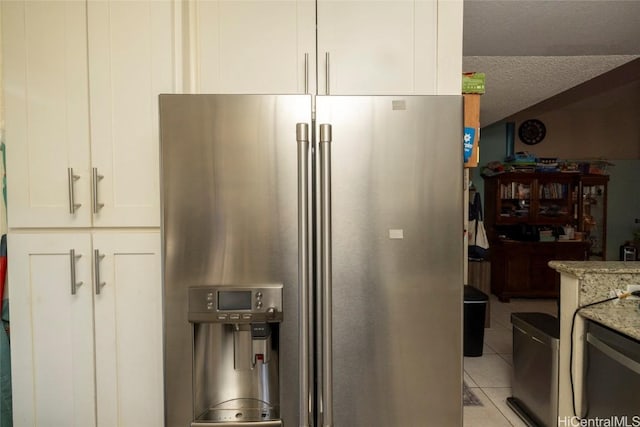 kitchen featuring light stone countertops, white cabinets, stainless steel fridge with ice dispenser, a textured ceiling, and light tile patterned floors