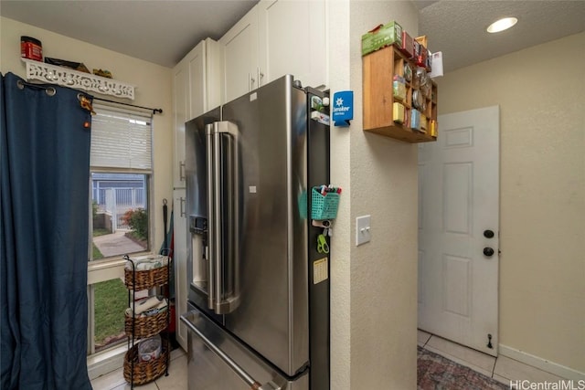 kitchen featuring white cabinets, high end fridge, light tile patterned floors, and a textured ceiling