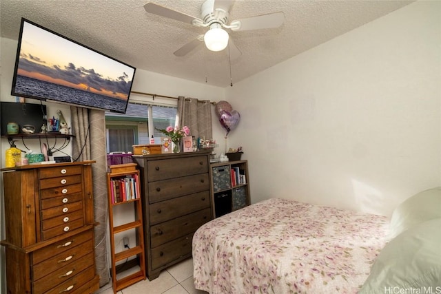 bedroom featuring ceiling fan, light tile patterned floors, and a textured ceiling