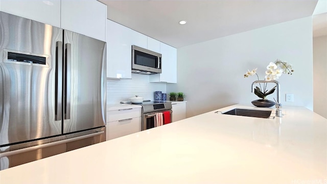 kitchen featuring appliances with stainless steel finishes, tasteful backsplash, white cabinetry, and sink