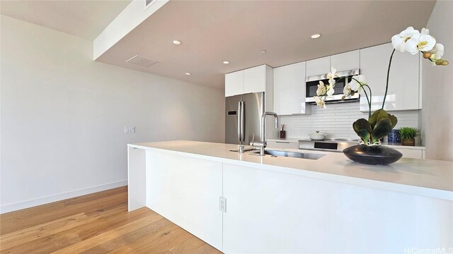 kitchen featuring white cabinets, light hardwood / wood-style floors, sink, and stainless steel appliances