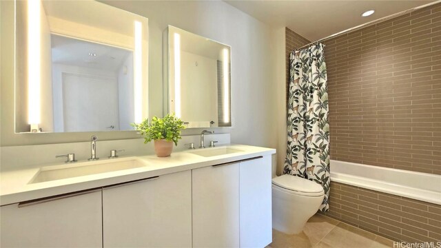 full bathroom with tile patterned floors, shower / bath combo with shower curtain, vanity, and toilet