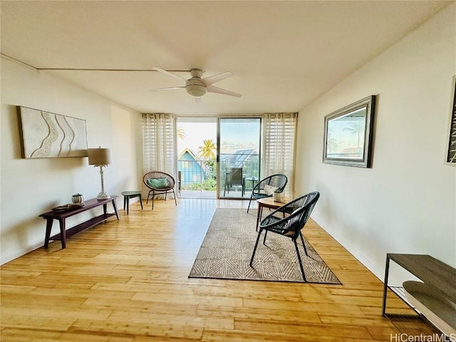 living area with plenty of natural light, light hardwood / wood-style floors, and floor to ceiling windows