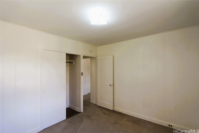 unfurnished bedroom with a closet and dark colored carpet