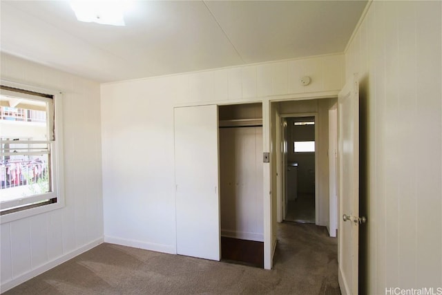 unfurnished bedroom featuring dark colored carpet and a closet