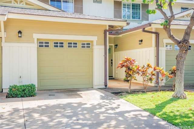 view of exterior entry with driveway, a shingled roof, board and batten siding, and an attached garage