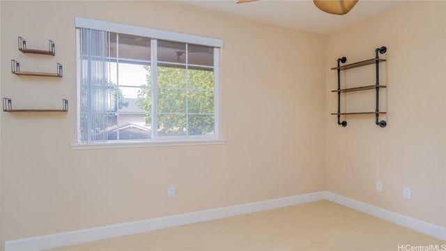 spare room featuring a ceiling fan and baseboards