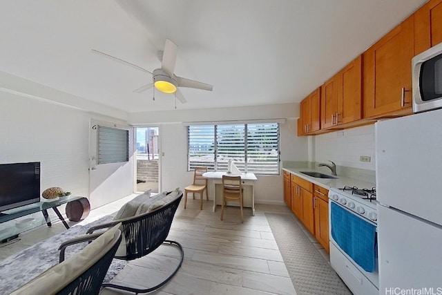 kitchen featuring decorative backsplash, ceiling fan, sink, and white appliances