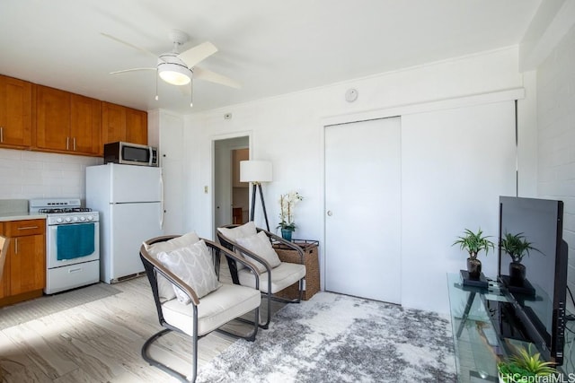 kitchen featuring tasteful backsplash, ceiling fan, light hardwood / wood-style flooring, and white appliances