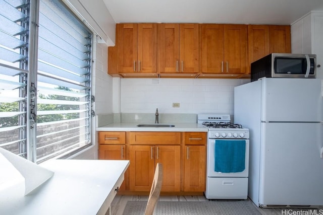 kitchen with white appliances, backsplash, and sink