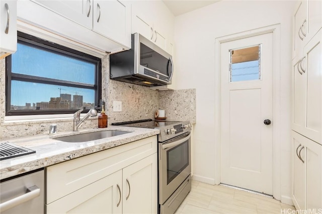 kitchen featuring decorative backsplash, light stone counters, stainless steel appliances, sink, and white cabinetry