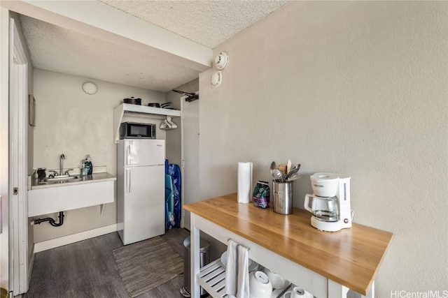 kitchen featuring sink, a textured ceiling, butcher block countertops, white fridge, and dark hardwood / wood-style flooring