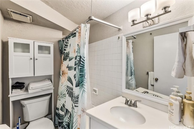 bathroom featuring a shower with shower curtain, vanity, toilet, and a textured ceiling