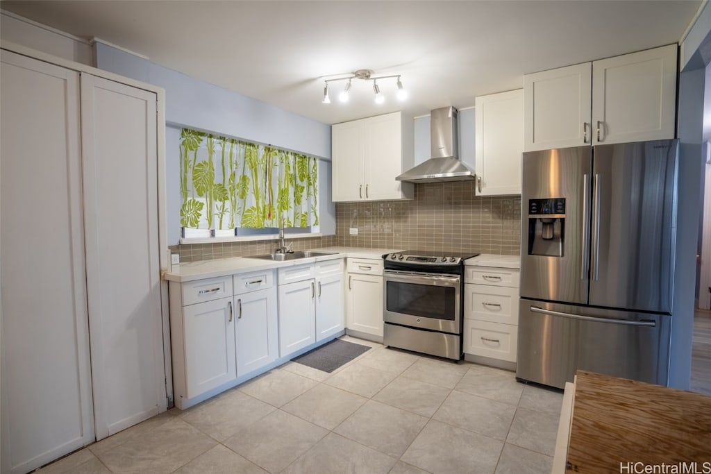 kitchen with decorative backsplash, wall chimney exhaust hood, stainless steel appliances, sink, and white cabinets