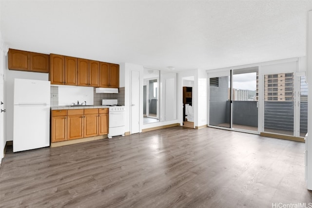 kitchen with tasteful backsplash, sink, white appliances, and light wood-type flooring