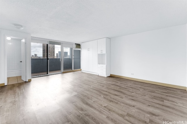 spare room with light wood-type flooring and a textured ceiling