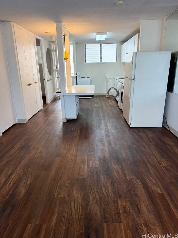 kitchen with white cabinetry, dark wood-type flooring, white refrigerator, washer / clothes dryer, and a breakfast bar area