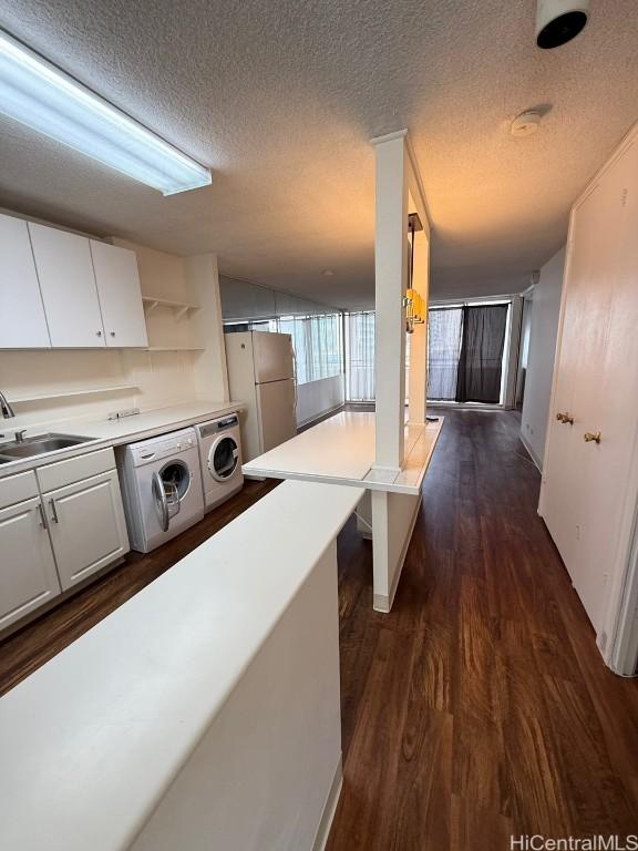 interior space featuring washer and dryer, sink, dark wood-type flooring, and a textured ceiling