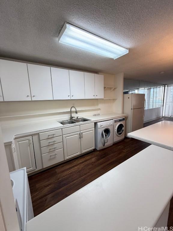 interior space featuring a textured ceiling, dark hardwood / wood-style floors, separate washer and dryer, and sink