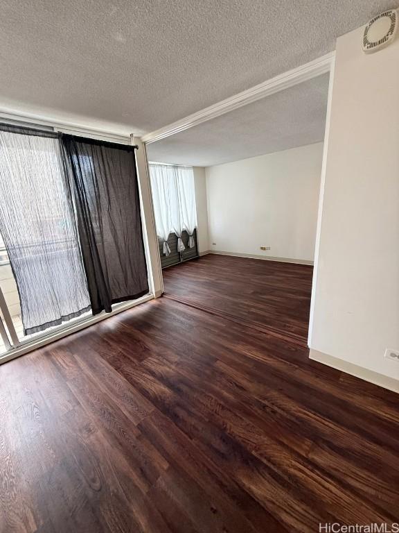 empty room featuring a textured ceiling and dark hardwood / wood-style floors