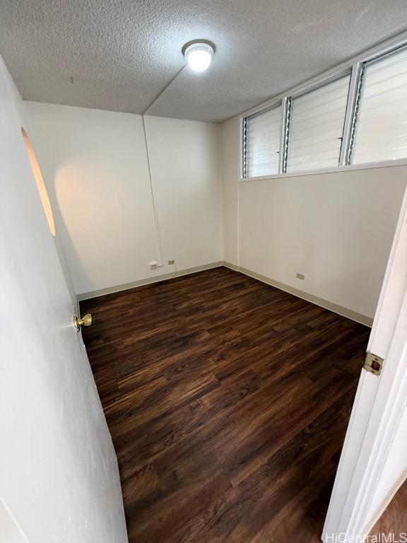 unfurnished room featuring a textured ceiling and dark wood-type flooring