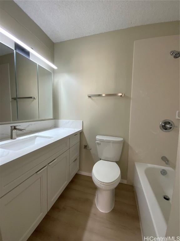 full bathroom featuring vanity, a textured ceiling, toilet, shower / bathing tub combination, and hardwood / wood-style flooring