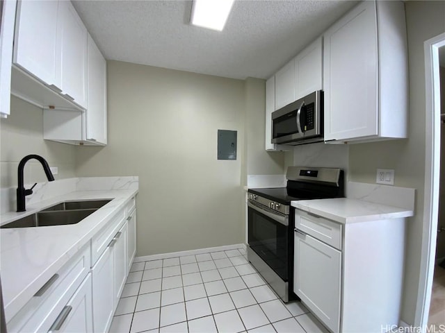 kitchen with light stone countertops, white cabinetry, sink, stainless steel appliances, and a textured ceiling