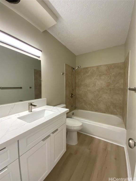 full bathroom featuring vanity, tiled shower / bath combo, toilet, a textured ceiling, and wood-type flooring