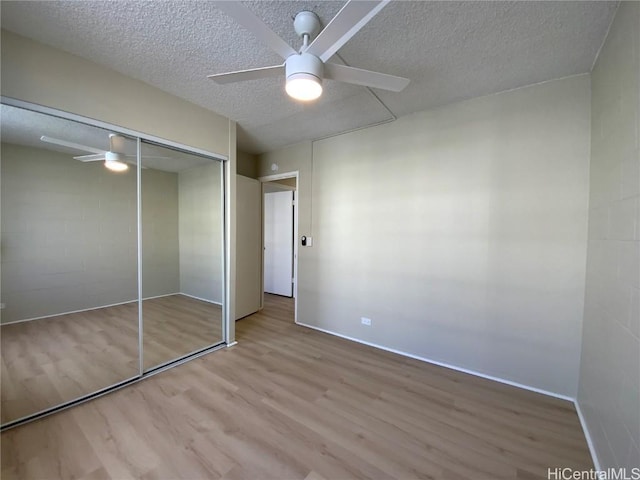 unfurnished bedroom with ceiling fan, light hardwood / wood-style floors, a textured ceiling, and a closet