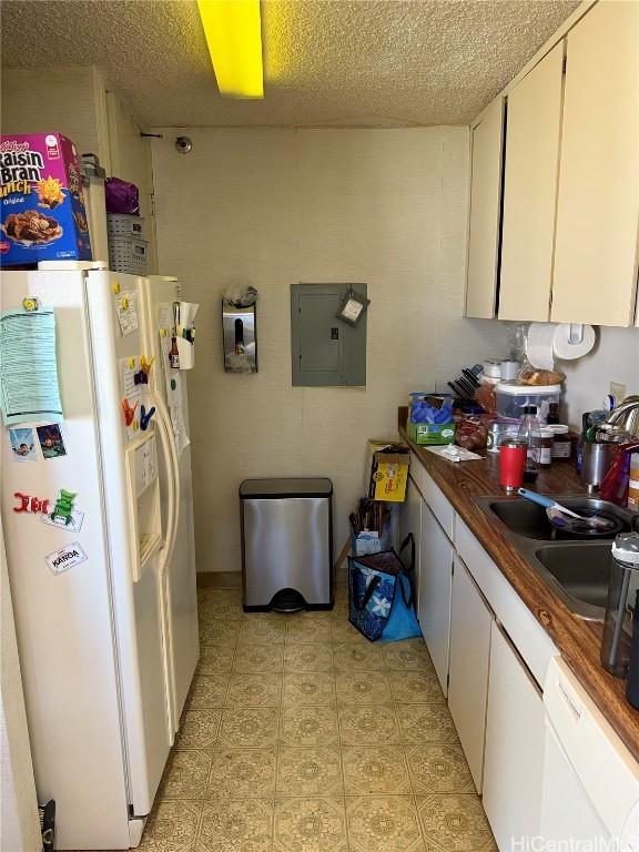 kitchen with electric panel, sink, white appliances, white cabinets, and wood counters