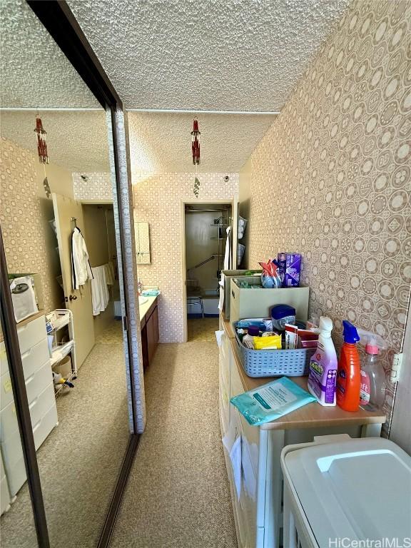 clothes washing area with a textured ceiling, light carpet, and independent washer and dryer