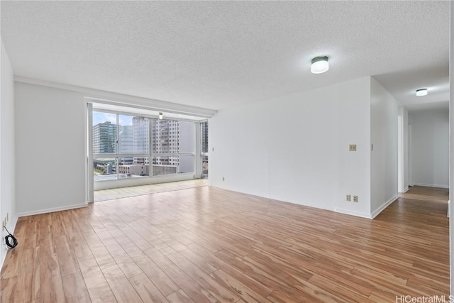 spare room with a textured ceiling and light wood-type flooring