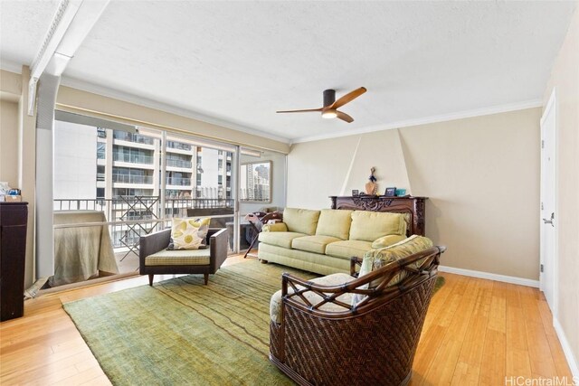 living room featuring a textured ceiling, light wood-type flooring, ceiling fan, and crown molding