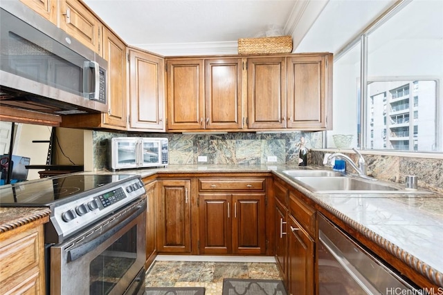 kitchen featuring backsplash, ornamental molding, appliances with stainless steel finishes, brown cabinetry, and a sink