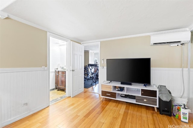 living area featuring a wall mounted air conditioner, light wood-style floors, ornamental molding, and wainscoting