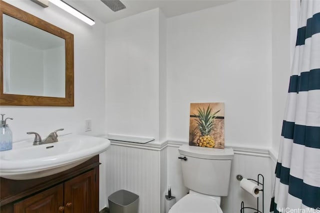 bathroom featuring a wainscoted wall, toilet, vanity, and a shower with shower curtain