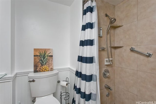 bathroom with wainscoting, toilet, and shower / bath combo with shower curtain