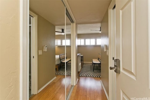 corridor featuring light wood-type flooring and baseboards