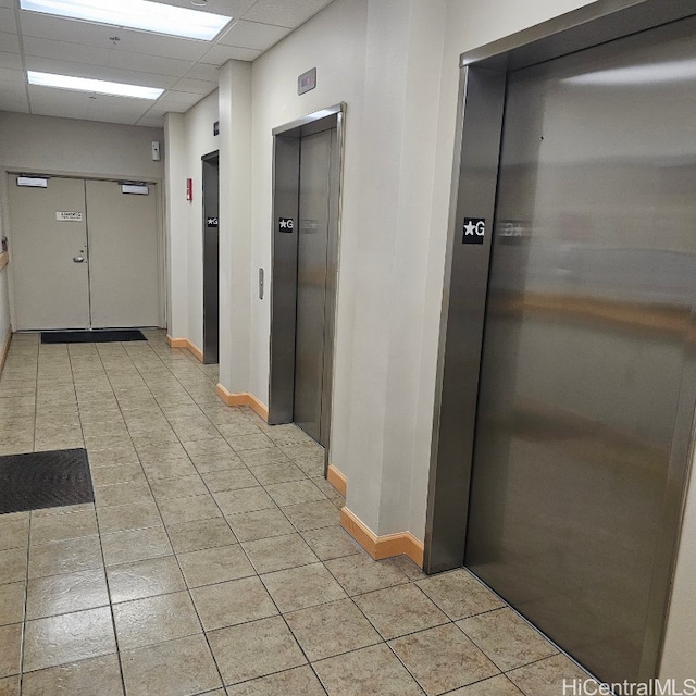 corridor with elevator and a drop ceiling