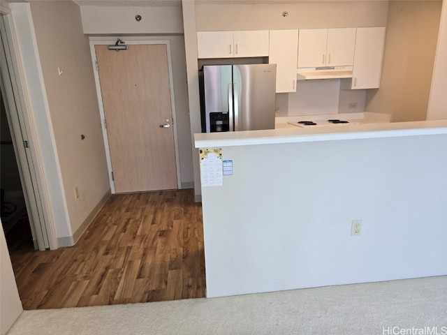 kitchen featuring white cabinets, stainless steel fridge, white cooktop, and kitchen peninsula