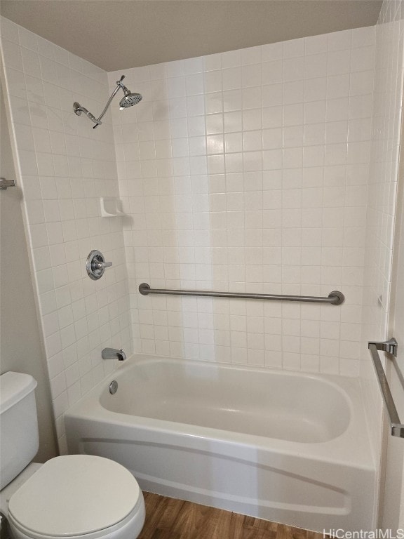 bathroom with hardwood / wood-style flooring, toilet, and tiled shower / bath