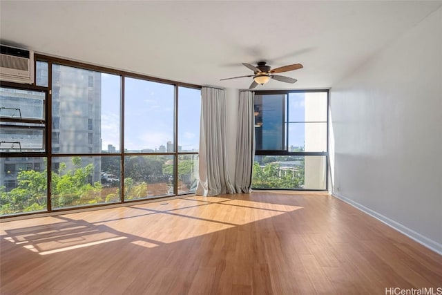 unfurnished room with hardwood / wood-style flooring, ceiling fan, and a wall of windows