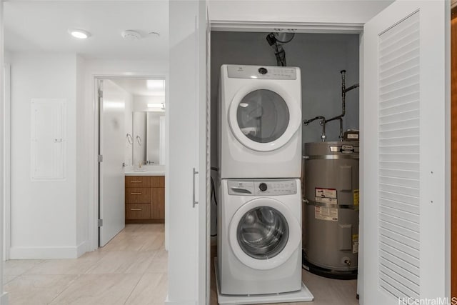 laundry area featuring light tile patterned flooring, stacked washing maching and dryer, and water heater