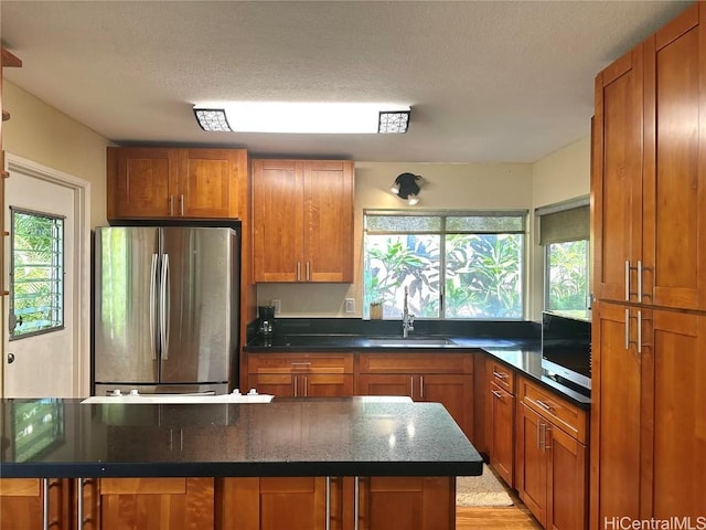 kitchen with a textured ceiling, light hardwood / wood-style floors, sink, and appliances with stainless steel finishes