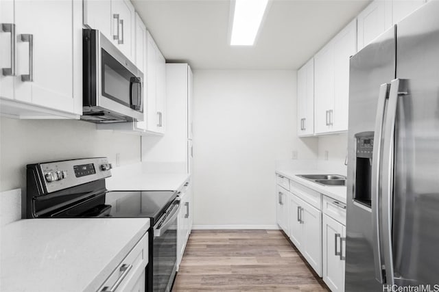 kitchen with sink, white cabinetry, stainless steel appliances, and light hardwood / wood-style flooring