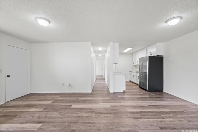 91-1022 Kaiau Ave Unit 3B, Kapolei, HI 96707 - kitchen featuring stainless steel refrigerator with ice dispenser, a textured ceiling, white cabinets, light countertops, and light wood-style flooring