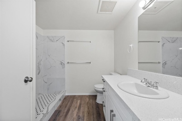 bathroom featuring hardwood / wood-style floors, vanity, toilet, and tiled shower