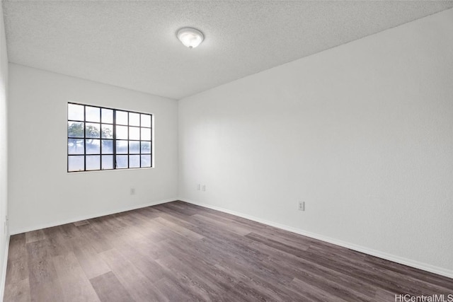 empty room featuring a textured ceiling and dark hardwood / wood-style floors